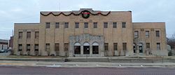 A two-story yellow brick building with three stone archways around the front doors